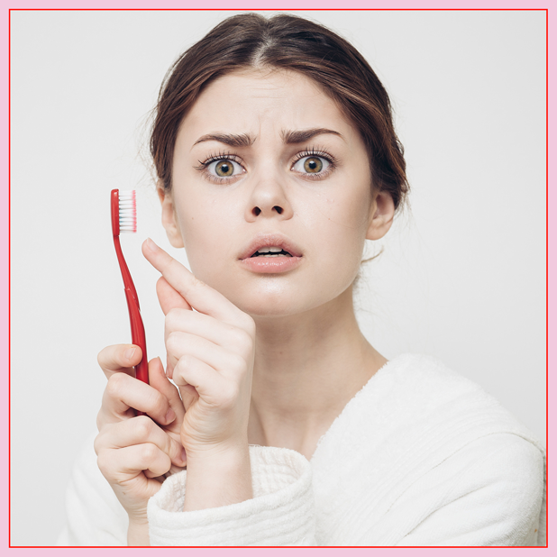 A woman pointing at her toothbrush.