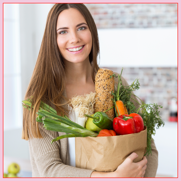 A woman holding healthy produce in a grocery bag.