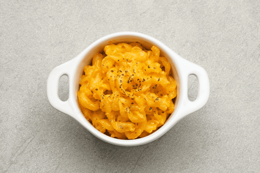 A close-up of a bowl filled with creamy macaroni and cheese, a comforting and indulgent dish.