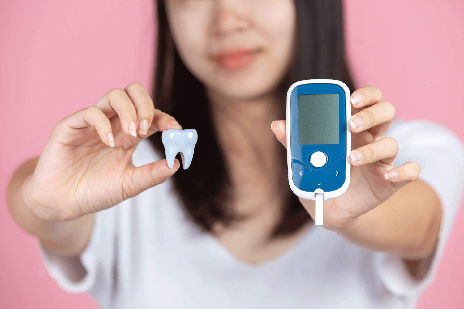 A photograph of a woman holding a tooth and a blood glucose meter.