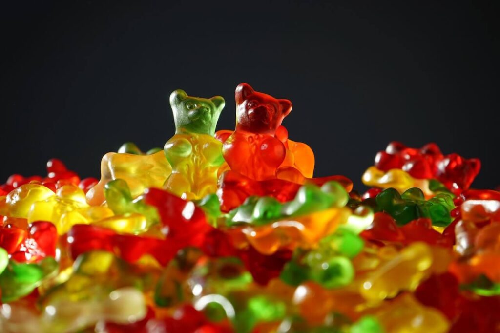 Close-up of a pile of gummy bears with two bears standing out against a black background.