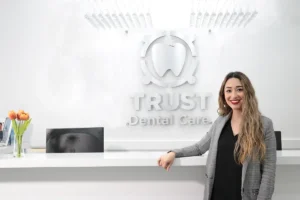 Tijuana Dentist for Dental Implants & Full Mouth Restoration in Mexico 13 young woman smiling at the reception of trust dental care with the background of trust dental care image