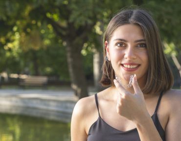 young woman with invisaligne in hands while smile with a beautiful tooth